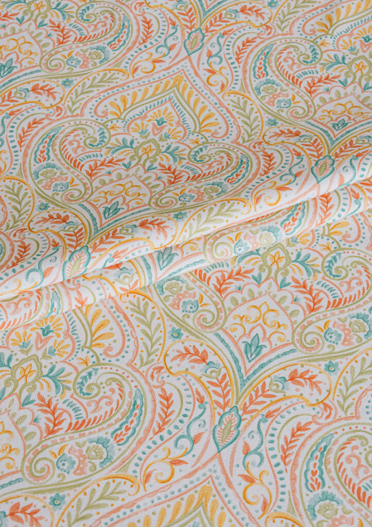 Fabric detail of LEGACY print with a symmetrical medallion and surrounding ornamental scrolls in rich, contrasting hues.