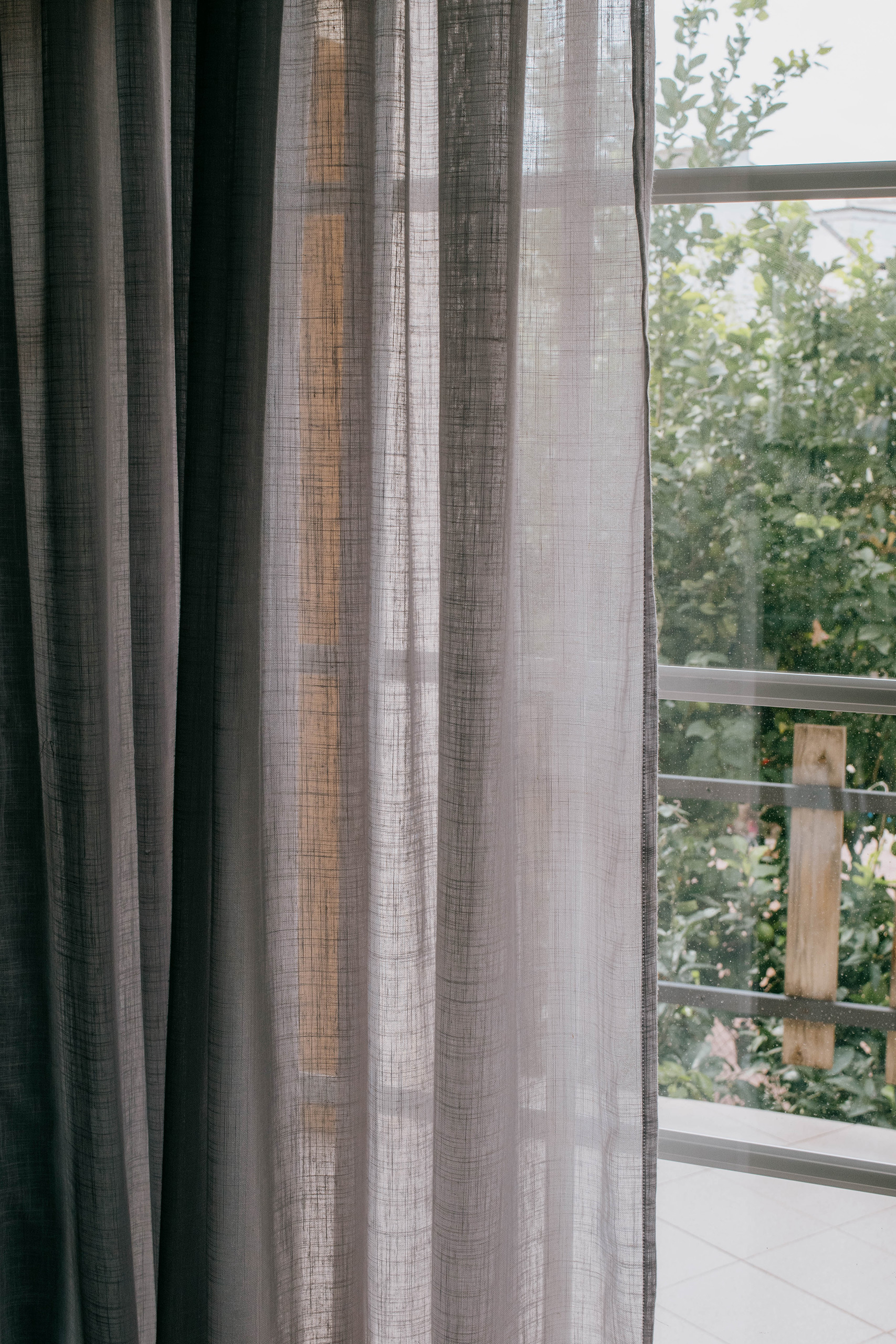 Living room with Mikonos curtain fabric in natural color, soft light filtering through