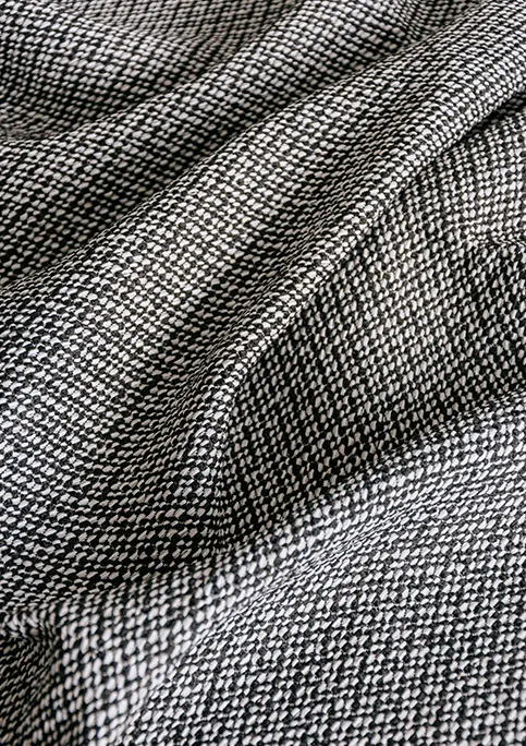 Close-up of Alika outdoor fabric showing textured weave and water-repellent finish in a solid color. Black color