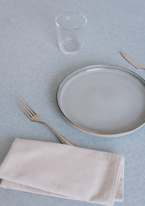 Alt text Dining table styled with blue LAGOS tablecloth and grey LAGOS napkins.