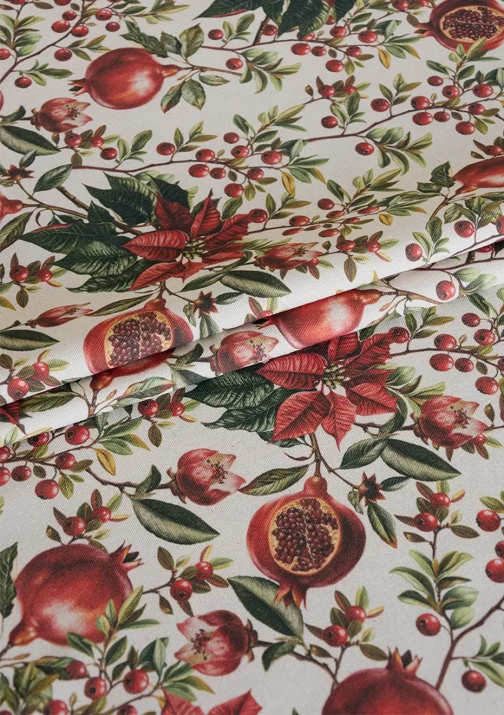 AYLON fabric, from GRENAT Collection. A bold botanical design featuring poinsettias and pomegranates. The red tones are more prominent here, giving the pattern a fuller and more decorative presence.
